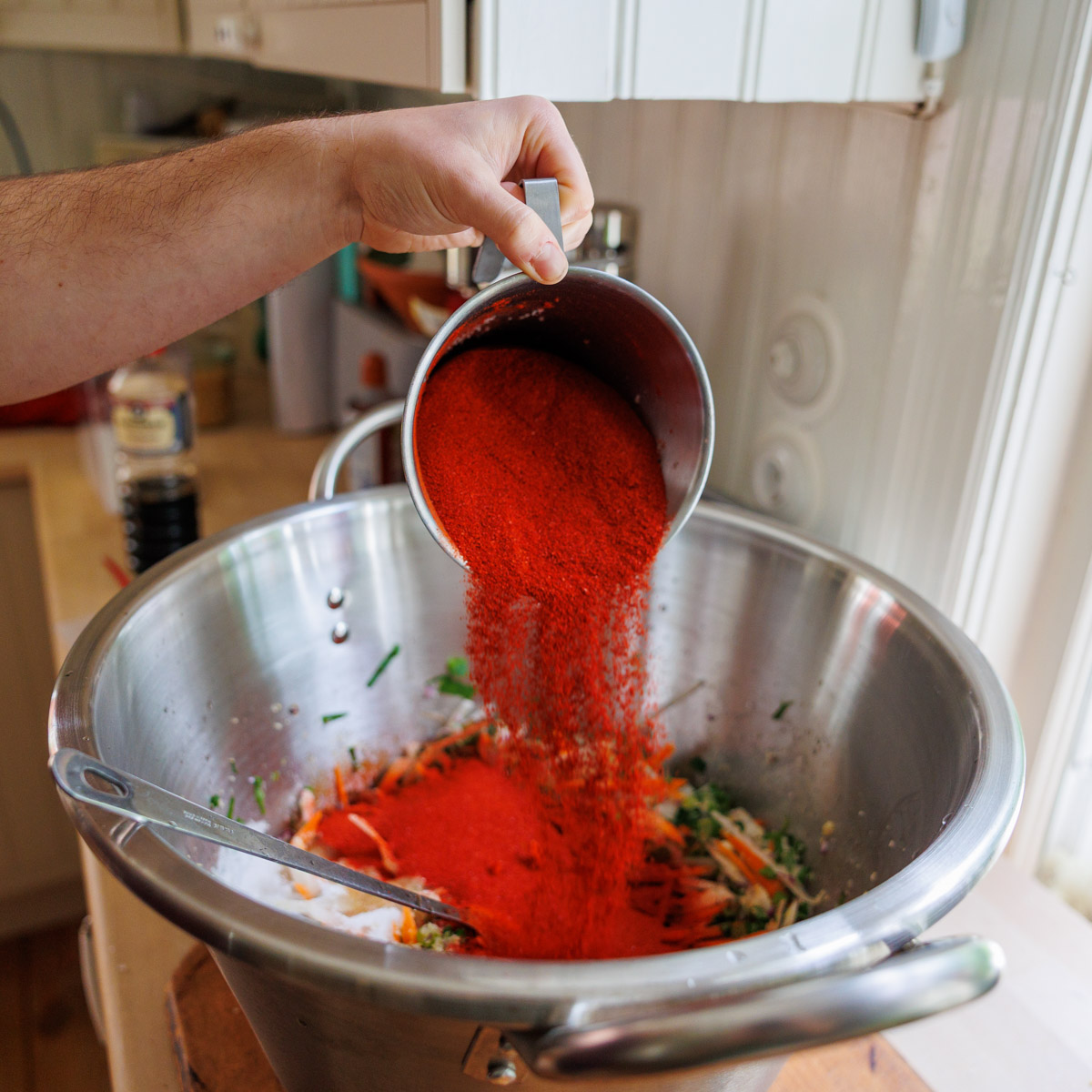 Gochugaru hälls över grönsaksblandning till kimchi