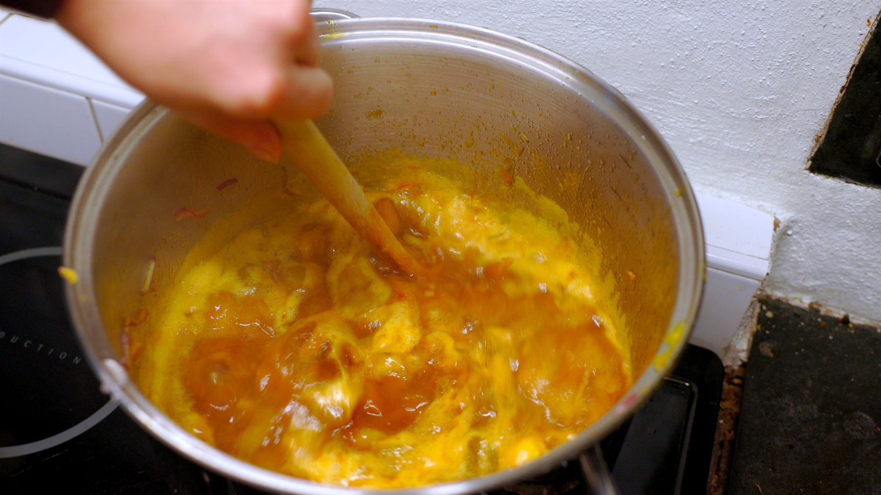 Rabarberchutney som har kokat ihop och fått en varm gul curryfärg.