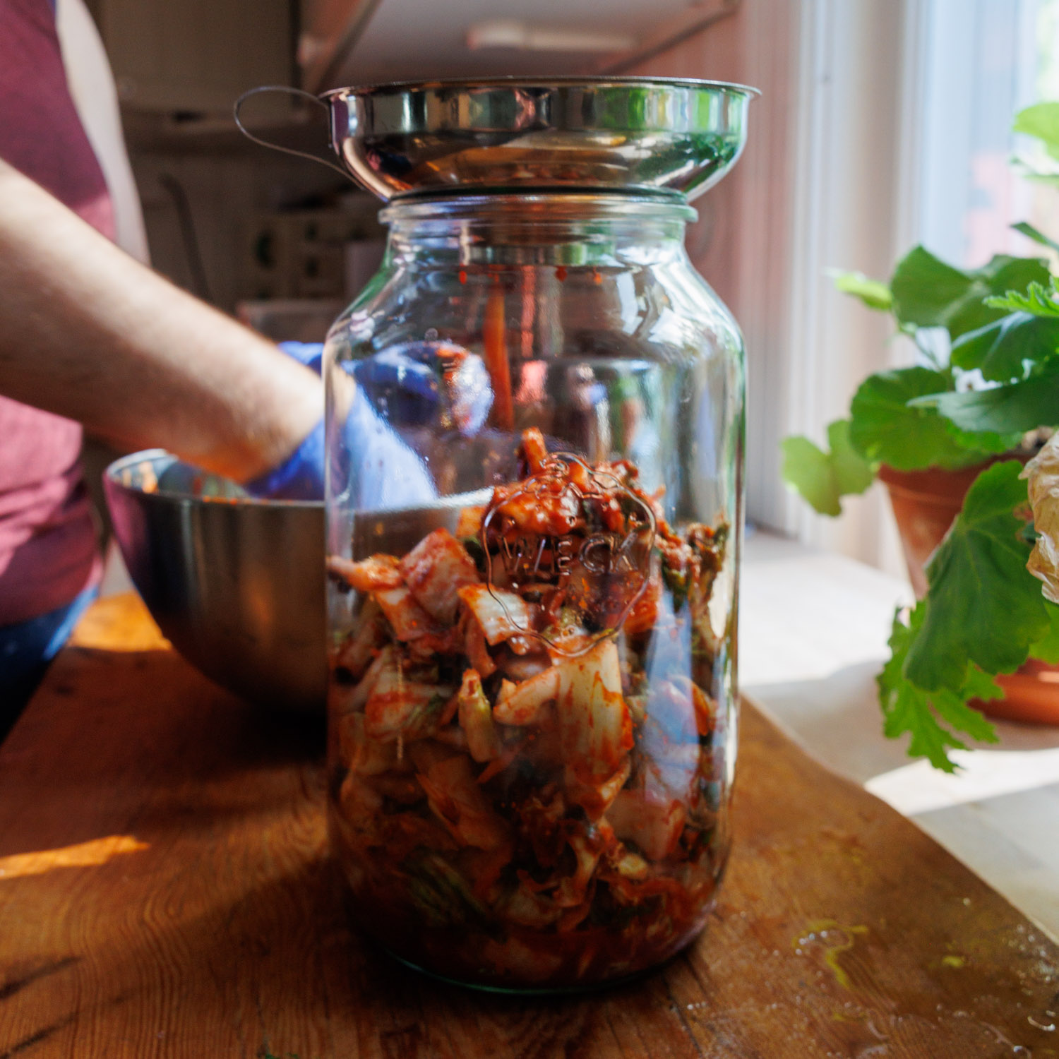 Kimchi fylls på i en stor glasburk.