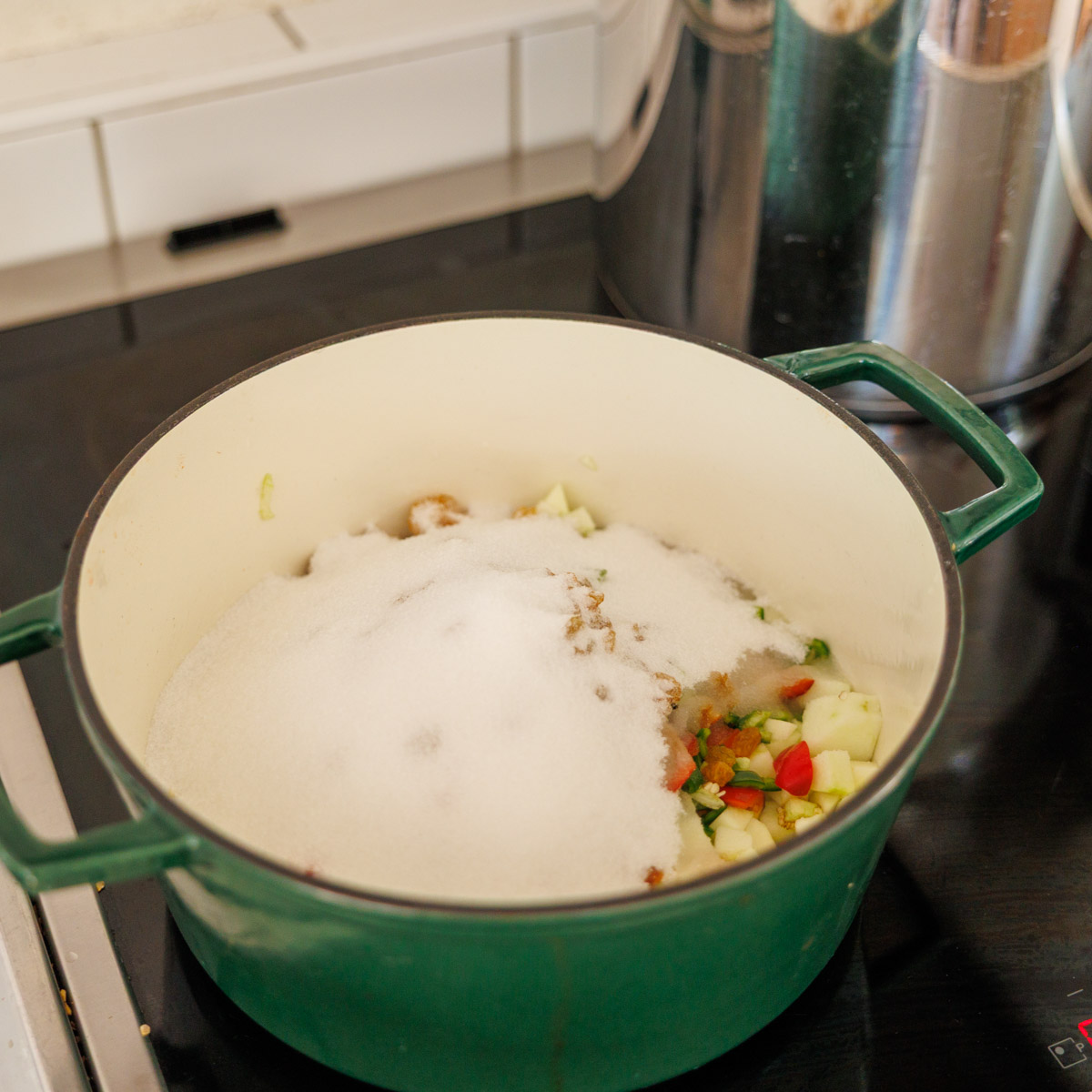 Äpple, chili, russin och socker i grytan före kokning